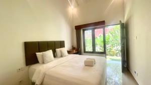 a bedroom with a large white bed with a window at Tegala Home in Payangan