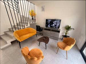 a living room with orange chairs and a television at Acogedora casa en Capittala Leon-Facturamos in Santa Gertrudis