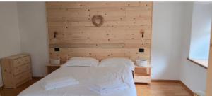 a bed in a room with a wooden wall at Rifugio di Niki in Falcade