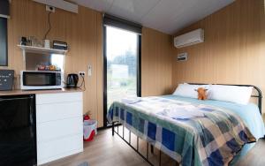 a room with a bed and a microwave and a kitchen at Bruce Farm Alpaca Cabin 1 by Tiny Away in Balclutha