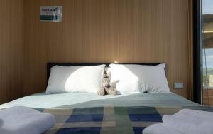 a stuffed animal sitting on top of a bed at Bruce Farm Alpaca Cabin 2 by Tiny Away in Balclutha +33 photos