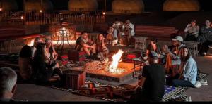 a group of people sitting around a fire at WADI RUM TARA lUXURY CAMP in Wadi Rum