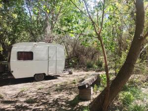 a white trailer is parked in the woods at Casa Rodante y Camping Los Retoños in San Marcos Sierras