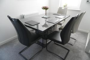 tavolo da pranzo con sedie nere e vaso di fiori di Detached Home in Bishopton a Bishopton Altre 14 foto