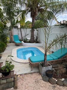 a swimming pool with two chairs and a palm tree at Maison avec piscine et rooftop à la Preneuse - 5min de la plage in Rivière Noire
