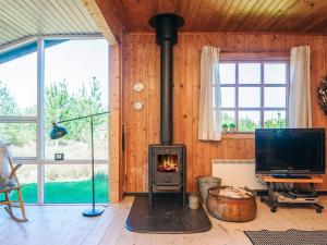 a fireplace in a living room with a tv and windows at 6 person holiday home in Rømø in Bolilmark