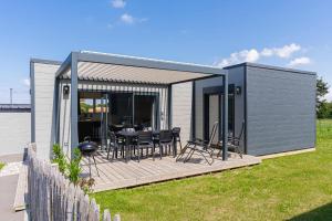 a tiny house with a table and chairs on a deck at ASNELLES chalet GOLD in Asnelles
