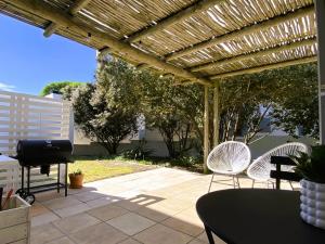 a patio with chairs and a wooden pergola at Namaste Cottage - Garden Facing 2-sleeper Hideaway in Paternoster