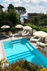 een blauw zwembad met parasols en stoelen bij Hotel Serenella in Sirmione