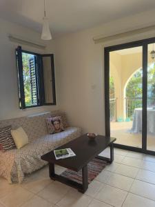 a living room with a couch and a table at Tranquil Poolside apartment with stunning views in Mazotos