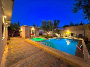 ein Swimmingpool in einem Hinterhof bei Nacht in der Unterkunft Villa Romantique à Marrakech Avec Piscine Privée & Jardin in Marrakesch