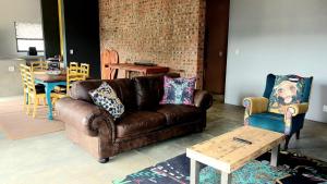 a living room with a brown leather couch and chairs at OppiStoep in Clarens