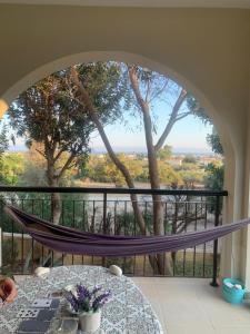 a room with a hammock on a balcony with a table at Tranquil Poolside apartment with stunning views in Mazotos