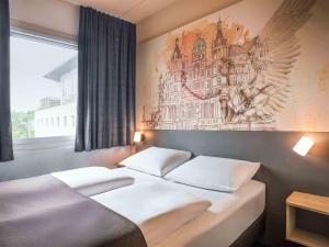 Un dormitorio con dos camas y un cuadro en la pared. en B&B Hotel Schwerin-Süd, en Schwerin