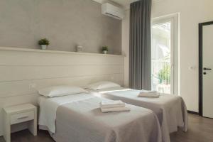 two beds in a room with white sheets at Hotel Hawaii Bed and Coffee in Riccione