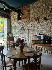una cucina con tavoli e sedie e un muro in pietra di la DROMOISE DU LOT a Saint-Sozy
