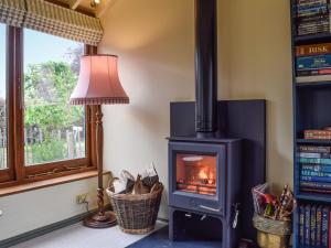 un poêle à bois dans une pièce avec une fenêtre dans l'établissement Lomond Cottage, à Garsington