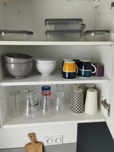 a kitchen shelf with bowls and other items on it at Studio au calme avec jardin in Trémuson +26 photos
