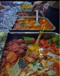 a buffet with many trays of food with a spoon at Wadi Rum Luxurious Camp View in Wadi Rum