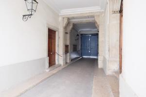 ein leerer Flur in einem alten Gebäude mit blauer Tür in der Unterkunft Honorê - Suites Bellecour in Lyon