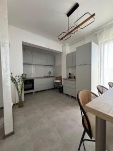 a kitchen with white cabinets and a table and chairs at Alia Residence in Buzau