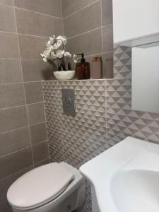 a bathroom with a toilet and a vase of flowers at Alia Residence in Buzau