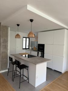 a kitchen with white cabinets and a island with bar stools at Casa do Tititos in Baiona +9 photos