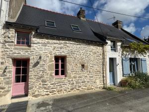 een stenen huis met rode ramen en een zwart dak bij La Maison Rose in Saint-Armel