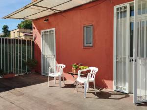 un patio con due sedie e un tavolo di fronte a una casa rossa di Il Gatto e Pirouette a Napoli