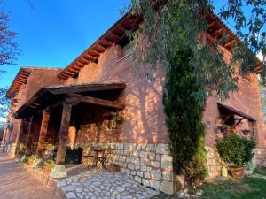 a red brick house with a tree in front of it at El Balcón De Alboreca in Sigüenza