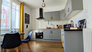 a kitchen with white cabinets and a table and chairs at La Petite Savane - Hyper centre-ville in Beauvais +8 photos