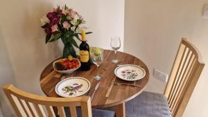 a wooden table with a vase of flowers and wine bottles at Cosy Bolt-hole escape for 2 in stunning valley in Stanford on Teme