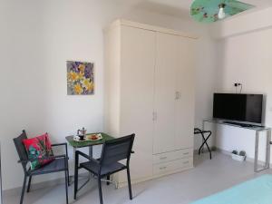 Una sala de estar con una mesa y sillas y un televisor. en B&B Altamarea, en Crotone