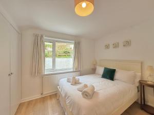 a bedroom with a white bed with towels on it at 3 bedroom cottage in the heart of Topsham with river views and parking in Topsham +7 photos