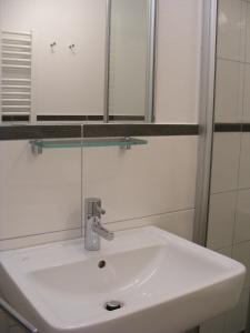 ein weißes Waschbecken im Bad mit Spiegel in der Unterkunft Ferienzimmer Lütt in Juliusruh