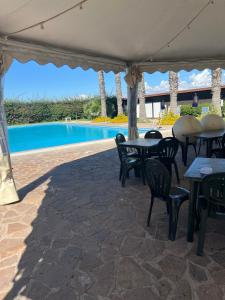 un patio con tavoli, sedie e piscina di Soggiorno e relax in eleganti villette interne al campo golf vicino al mare a due passi da Roma ad Ardea Altre 68 foto