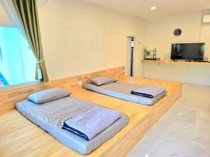 two beds sitting on a wooden floor in a room at Waew Arun Garden Resort in Ban Na Chik