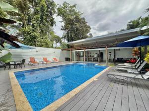 a swimming pool with chairs and an umbrella on a wooden deck at Standard King Room in Punta Uva