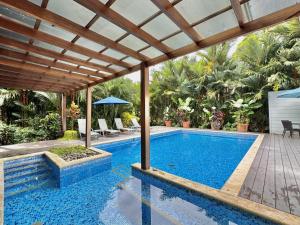 an outdoor swimming pool with a wooden pergola and a swimming poolvisor at Standard King Room in Punta Uva +4 photos