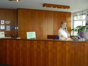 a woman talking on a phone at a reception desk at Hotel Stadt Norderstedt in Norderstedt