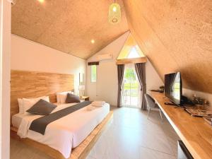 a bedroom with a large bed and a television at Waew Arun Garden Resort in Ban Na Chik