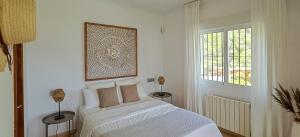 a white bedroom with a bed and a window at Casa de las Montañas in Parcent