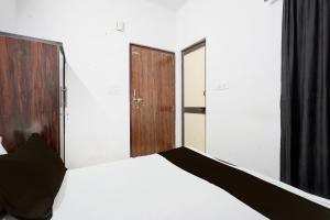コーターにあるHotel O Shri Panchmukhi Residency Baran Roadの白いベッドと木製のドアが備わるベッドルーム1室が備わります。