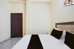 1 dormitorio con 1 cama blanca grande con almohadas negras en Hotel O Vip Stay Inn, en Ghaziabad 22 fotos más