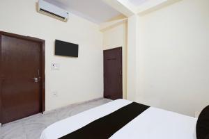 1 dormitorio con cama y puerta marrón en Hotel O Vip Stay Inn, en Ghaziabad