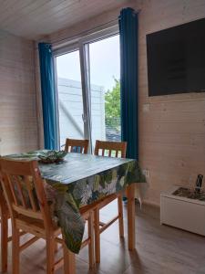 a dining room with a table and chairs and a television at Domki Turkusowe Zacisze in Sarbinowo