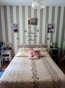 a bedroom with a large bed and striped walls at Le nid de mésanges in Chauffour-sur-Vell