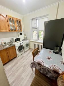 a kitchen with a table and a stove top oven at Авангард 4-12 in Atyraū