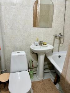 a bathroom with a toilet and a sink and a tub at Авангард 4-12 in Atyraū +1 photo