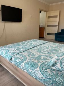 a bedroom with a bed with a television on the wall at Авангард 4-12 in Atyrau +1 photo